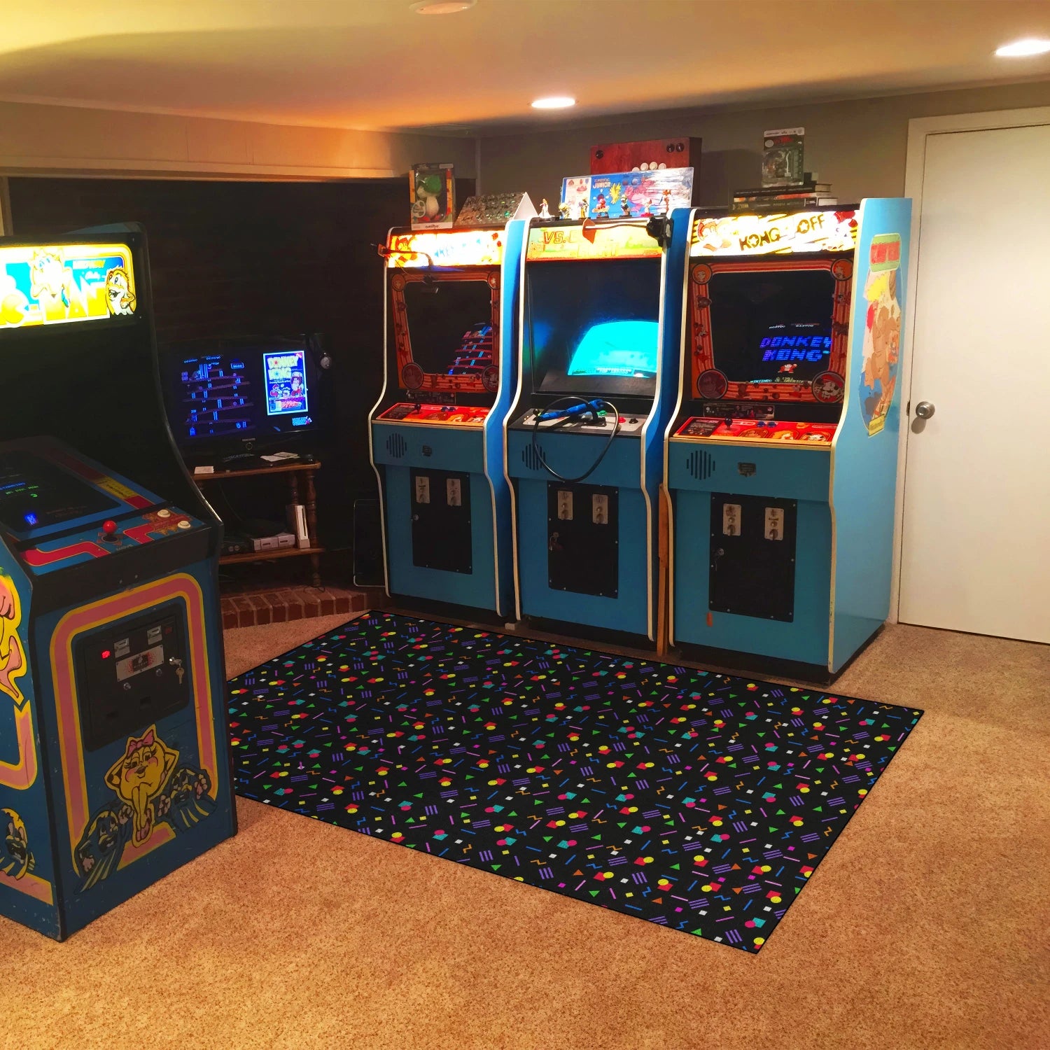 Collection of vintage arcade machines in a room with a colorful rug.