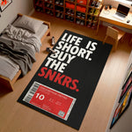 Sneaker-themed rug with 'Life is Short, Buy the Snkrs' text in a bedroom setting.

