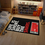 Room with a rug featuring 'Life is short, buy the SNKRS' text and a sneaker rack.

