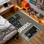 Gray rug with 'Life is short, buy the sneakers' text in a bedroom setting.

