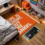 Room interior with an orange rug featuring text, a bed, and shelves with shoes.

