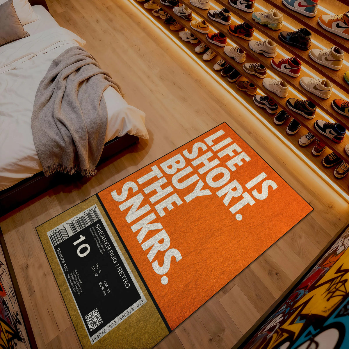 Orange doormat with text on a wooden floor next to a bed and shoe rack.

