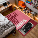 Room interior with a pink rug featuring text, shelves with shoes, and a bed.

