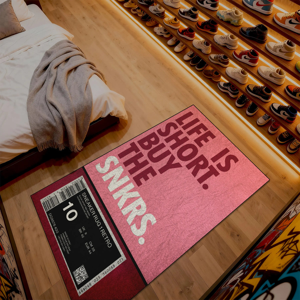 Pink doormat with text on a wooden floor next to a bed and shoe rack.

