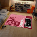 Room interior with a pink rug featuring text and a shoe rack in the background.


