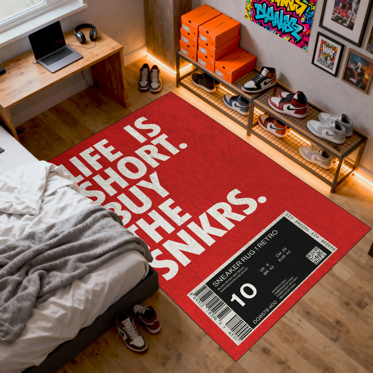 Red rug with 'Life is short, buy the sneakers' text in a room with shoes and a laptop.

