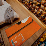 Orange mat with a label on a wooden floor next to a bed and shoe rack.


