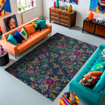 Colorful living room with an orange sofa, turquoise chair, and a patterned rug.